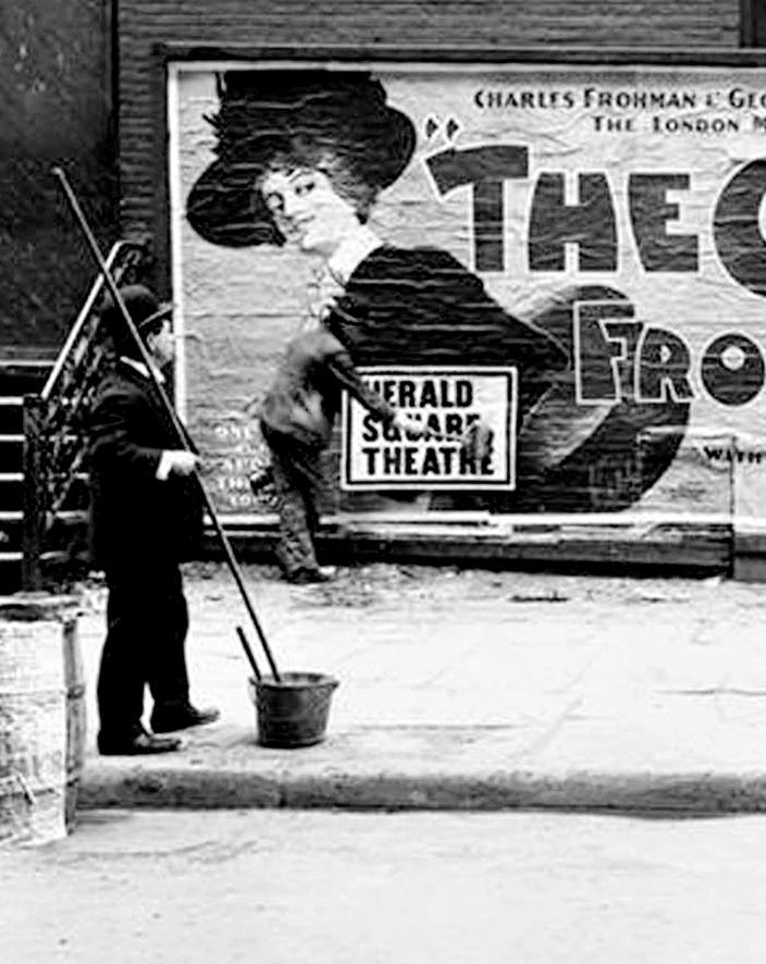 A billposter with his long brush beside a freshly pasted poster, 1904.