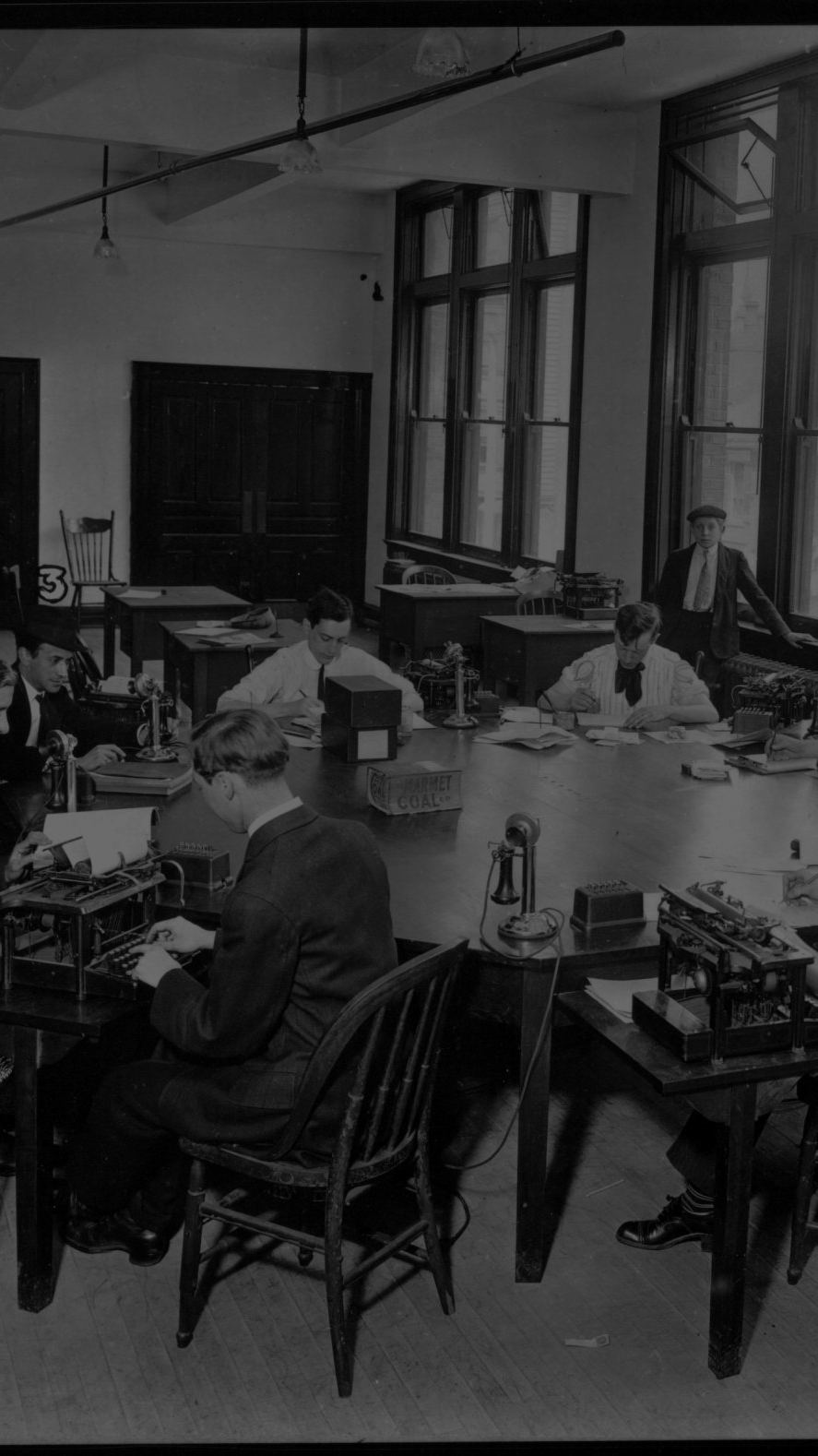 Editors at a round table with typewriters choosing headlines, the Cincinnati Post, 1910.
