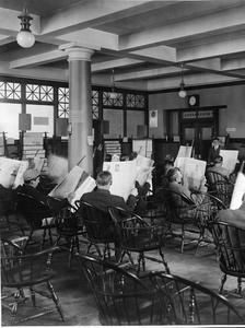 Men reading newspapers in a library reading room, Seattle, around 1910.