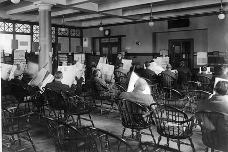 Newspaper readers in wooden chairs, Seattle, around 1910.