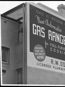 The side of a building painted with an advertisement, 1930s.